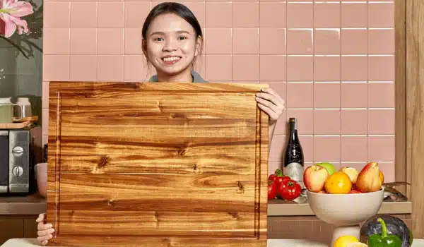 Smiling woman showcasing the best large wood cutting board with premium acacia wood and juice groove in a modern kitchen.
